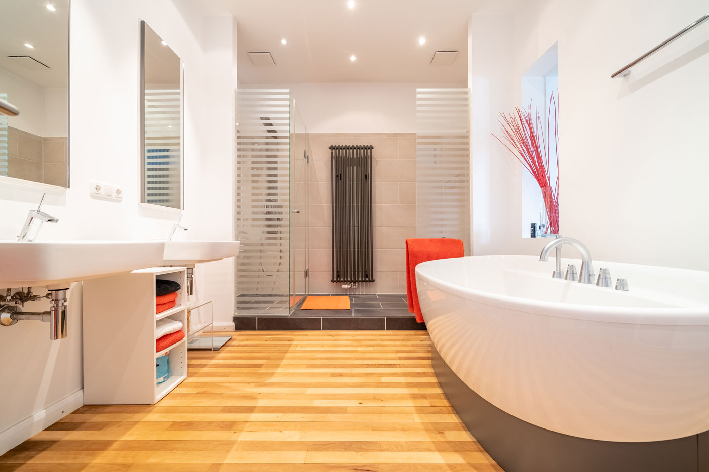 Modernes Badezimmer mit freistehender Badewanne, Doppelwaschbecken und ebenerdiger Dusche auf Holzboden