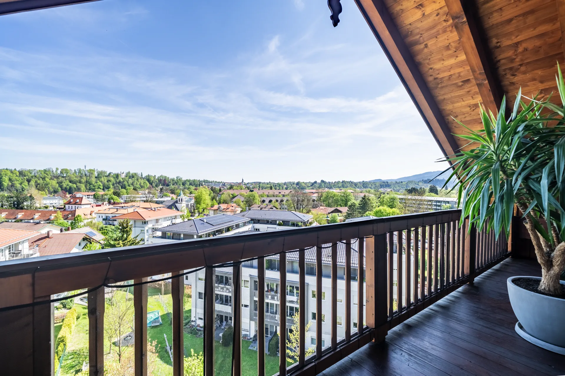 Balkon mit Holzgeländer und Blick über Bad Tölz bei blauem Himmel